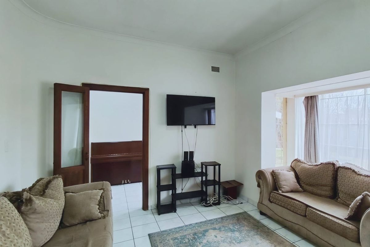 A living room featuring tiled flooring, a timber door frame, and a recessed window area, providing a functional space for relaxation.