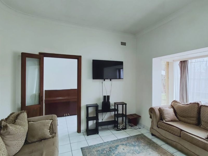 A living room featuring tiled flooring, a timber door frame, and a recessed window area, providing a functional space for relaxation.