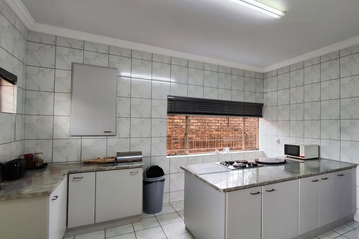 A functional kitchen featuring granite countertops, built-in gas hob, and tiled wall finishes, offering a clean and practical workspace.