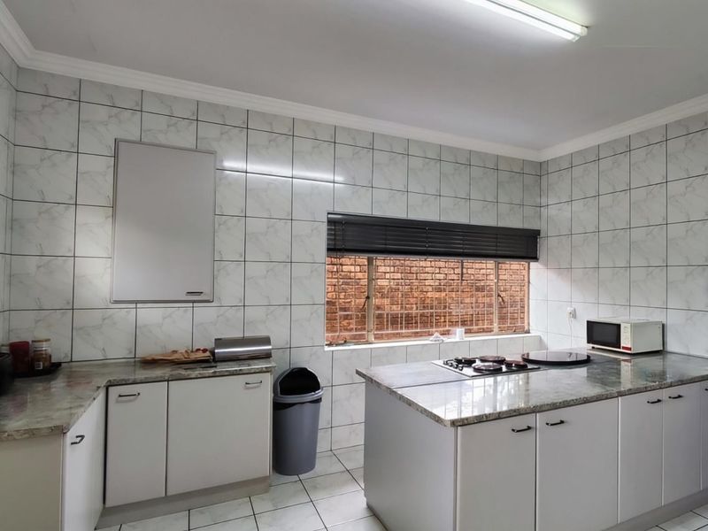 A functional kitchen featuring granite countertops, built-in gas hob, and tiled wall finishes, offering a clean and practical workspace.