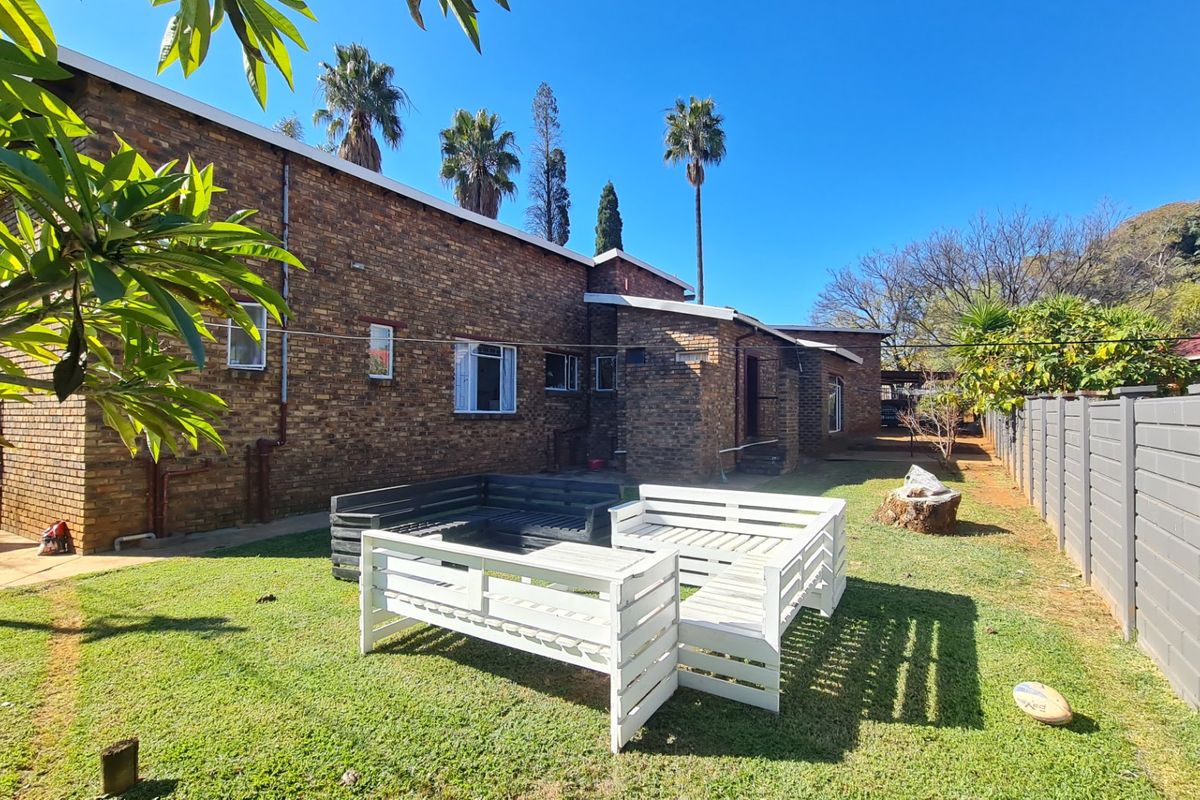 Rear view of the property featuring a face brick exterior, established lawn, and perimeter fencing.