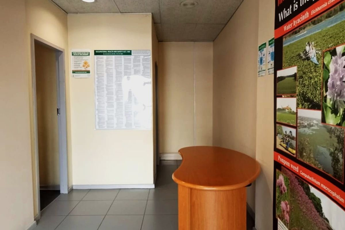 A functional commercial entry area featuring tiled flooring, a suspended ceiling with recessed lighting, and wall-mounted informational signage.