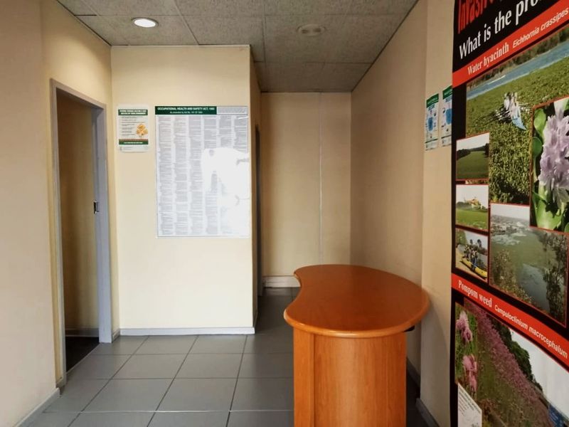 A functional commercial entry area featuring tiled flooring, a suspended ceiling with recessed lighting, and wall-mounted informational signage.