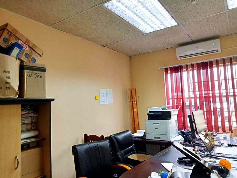 A functional commercial office space featuring a suspended ceiling, recessed lighting, and a wall-mounted air conditioning unit.