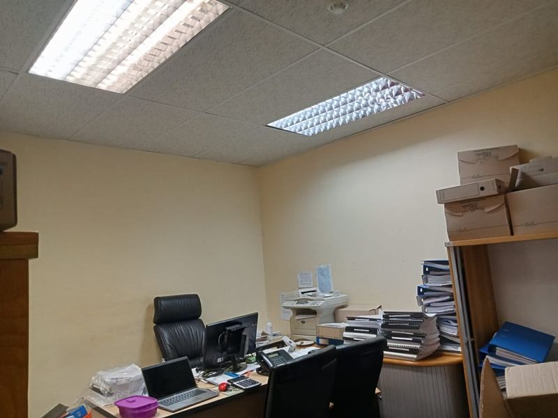 A functional commercial office space featuring a suspended ceiling with recessed lighting, providing a practical work environment.