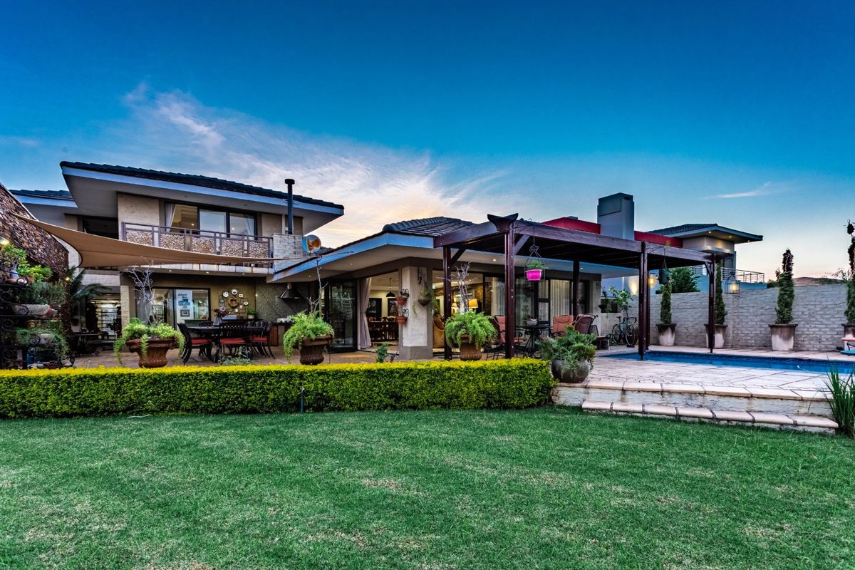 Spacious rear exterior featuring a covered patio, swimming pool, landscaped garden, and multi-level architectural design with integrated outdoor living spaces.