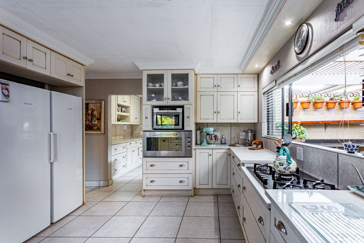 A well-appointed kitchen featuring classic cabinetry, built-in oven and microwave, gas hob, and a convenient adjoining scullery area with tiled flooring.