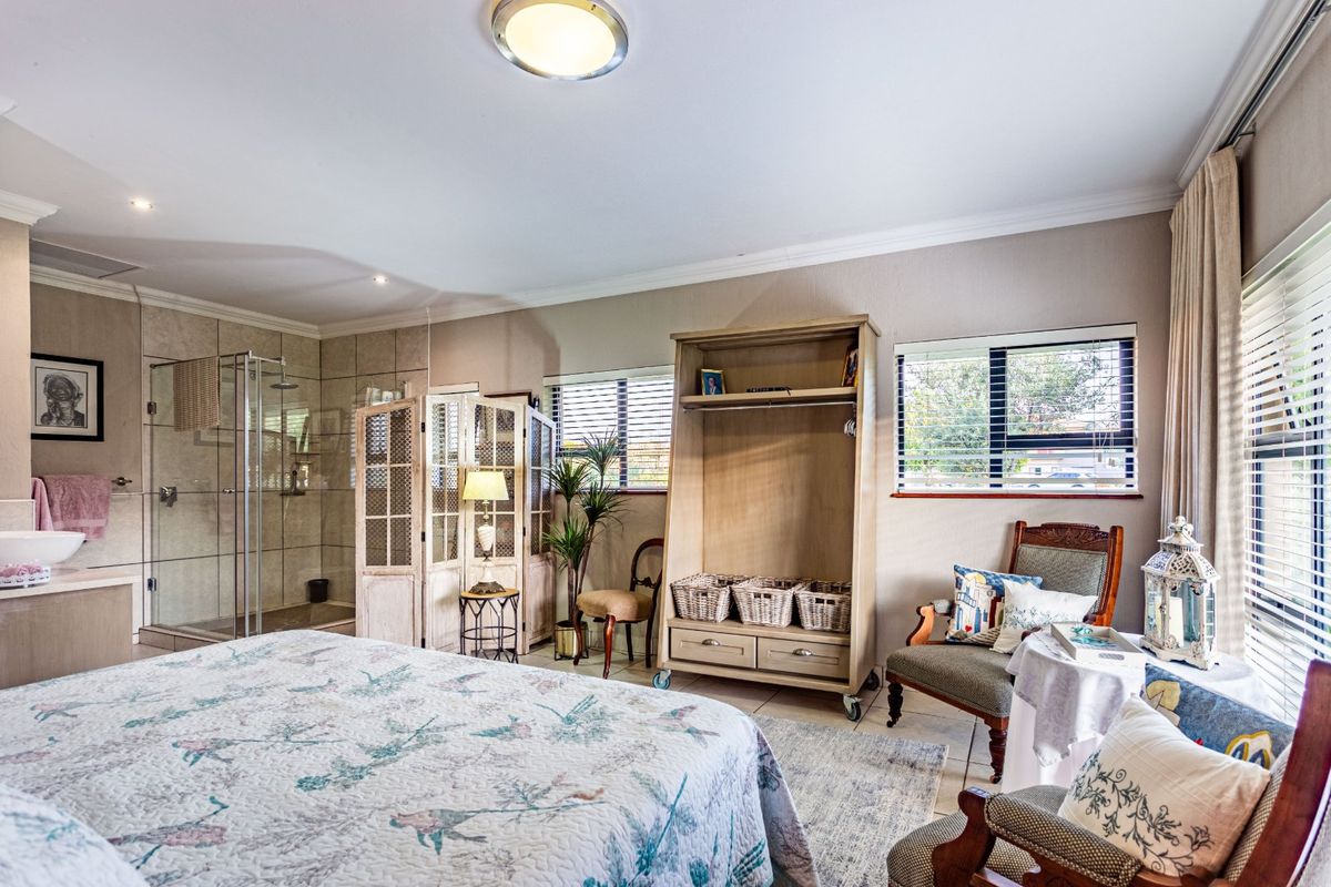 Spacious bedroom featuring an integrated en-suite bathroom with a glass-enclosed shower, tiled flooring, and large windows allowing for ample natural light.