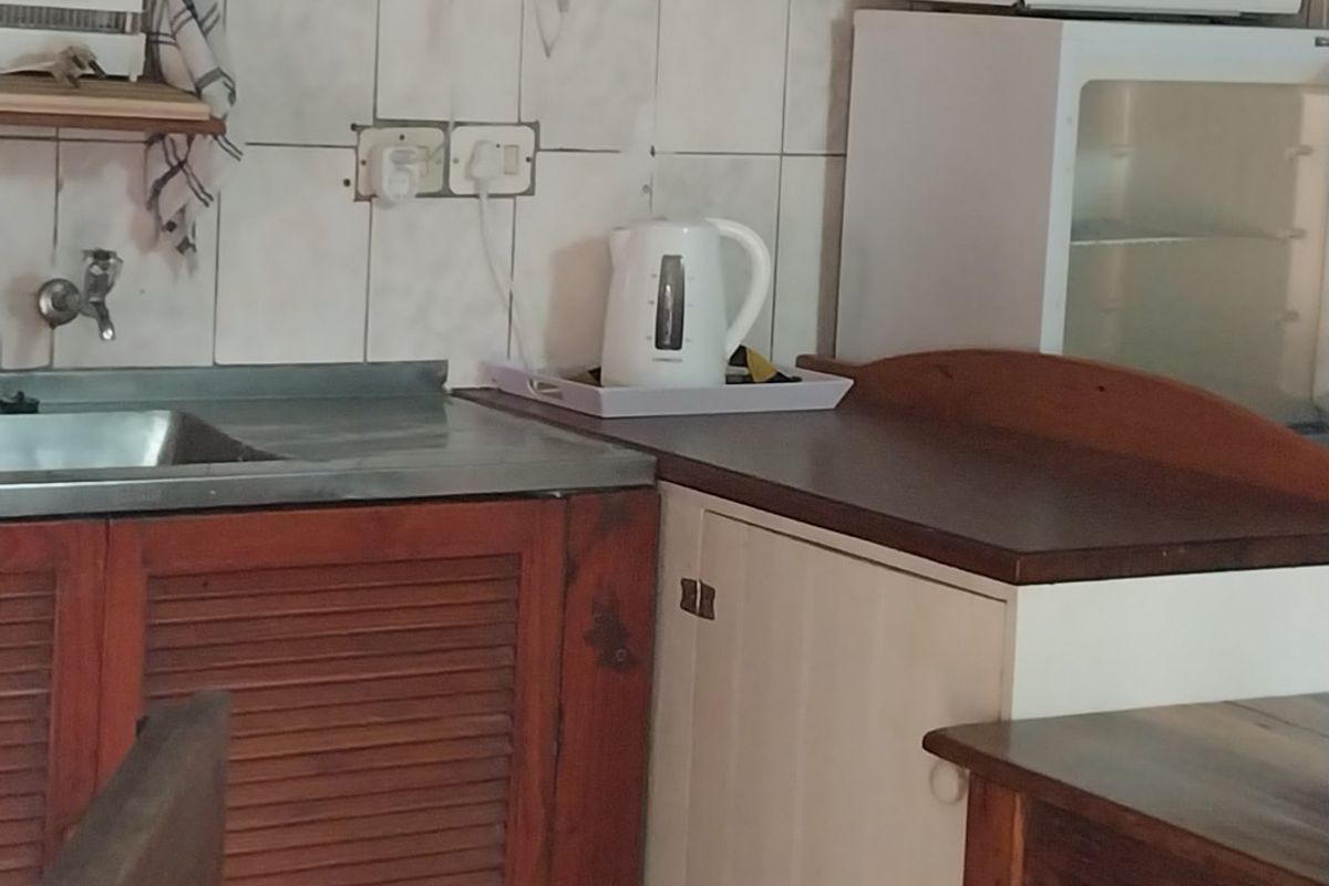 A compact kitchen area featuring a stainless steel sink, tiled backsplash, and built-in cabinetry with a microwave space.