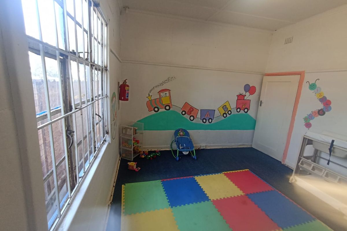 A bedroom space currently utilized as a nursery, featuring steel-framed windows and painted wall murals.