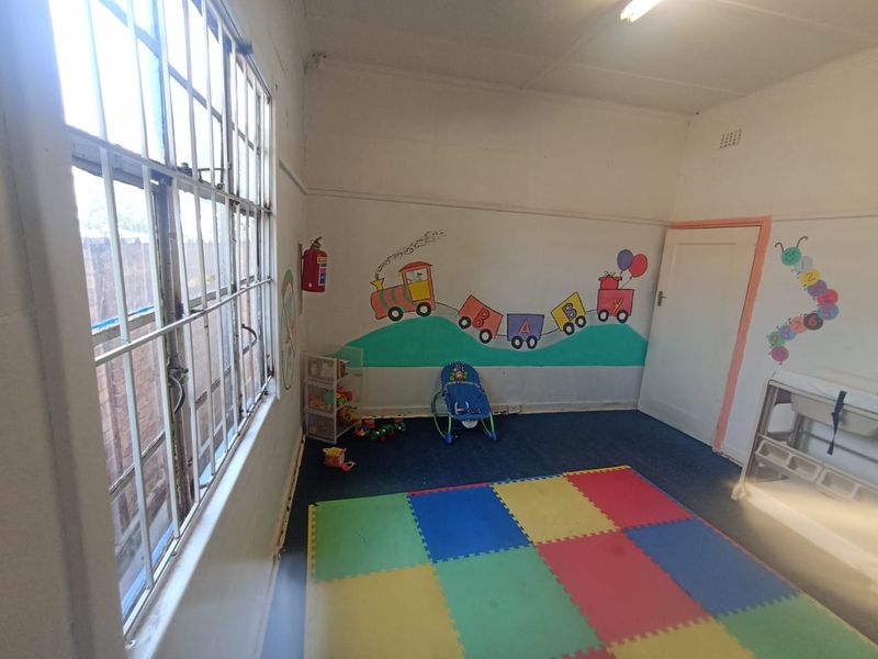 A bedroom space currently utilized as a nursery, featuring steel-framed windows and painted wall murals.