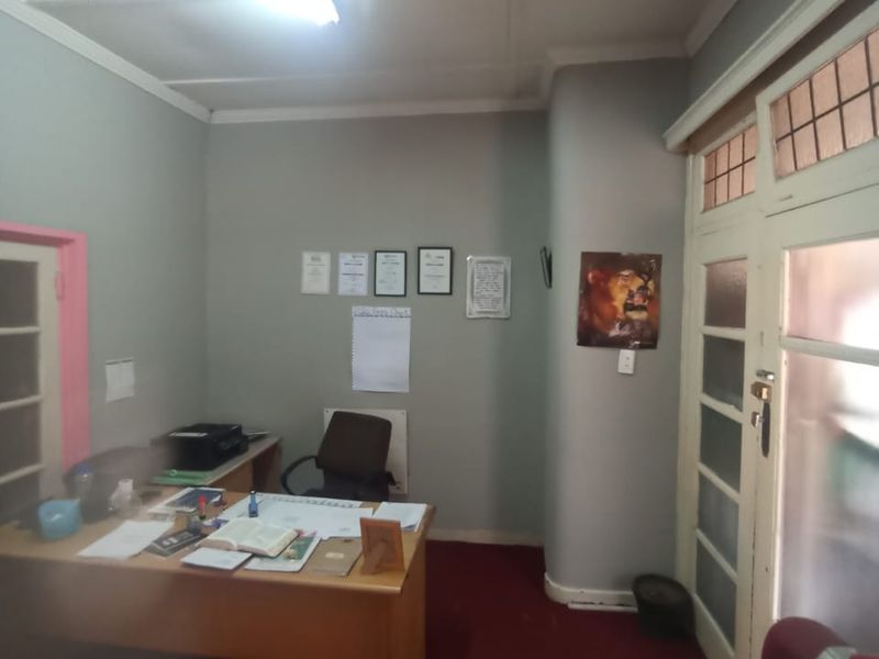 A functional office space featuring a leaded glass door and overhead fluorescent lighting, suitable for a home workspace.