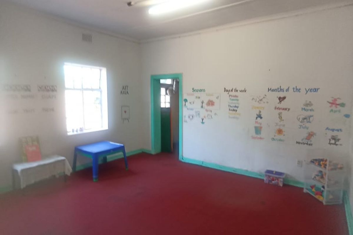A sparsely furnished room with red carpeting and basic lighting, currently utilized as a classroom space.