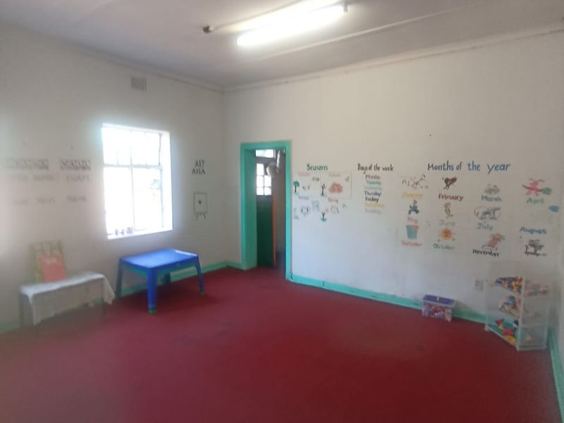 A sparsely furnished room with red carpeting and basic lighting, currently utilized as a classroom space.