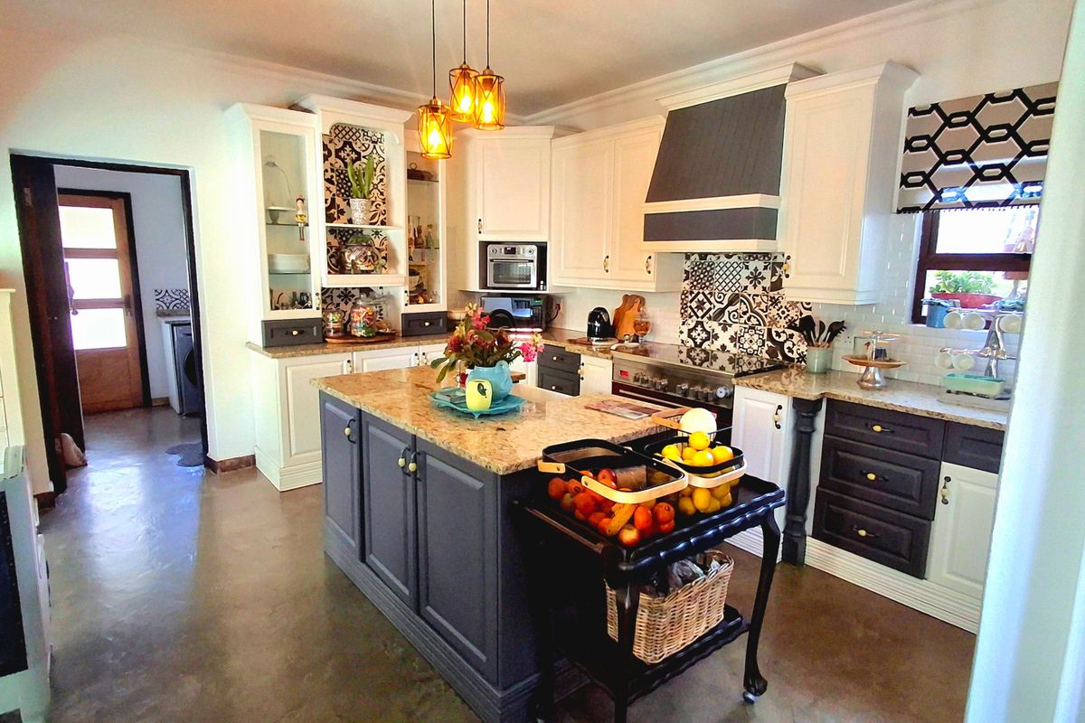 A well-appointed kitchen featuring a central island with granite countertops, built-in appliances, decorative tile backsplash, and stylish pendant lighting.