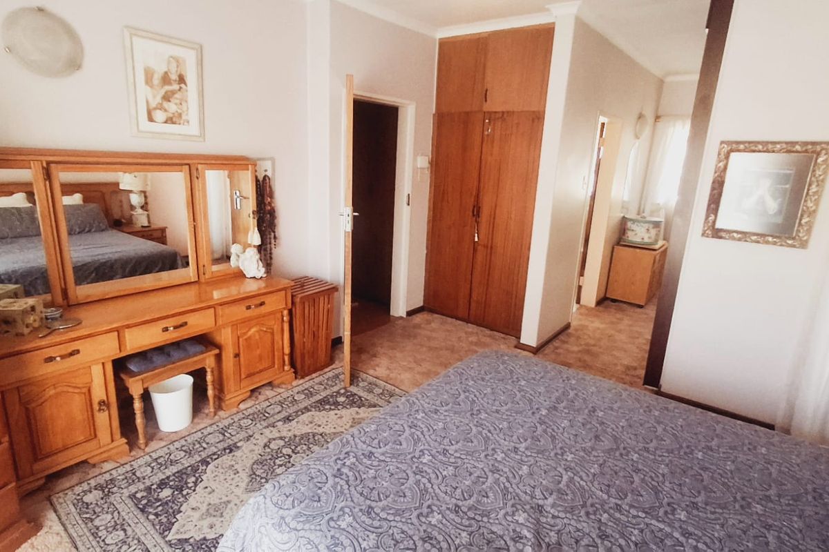 A bedroom featuring built-in wooden cupboards and carpeted flooring, offering a functional layout with traditional finishes.