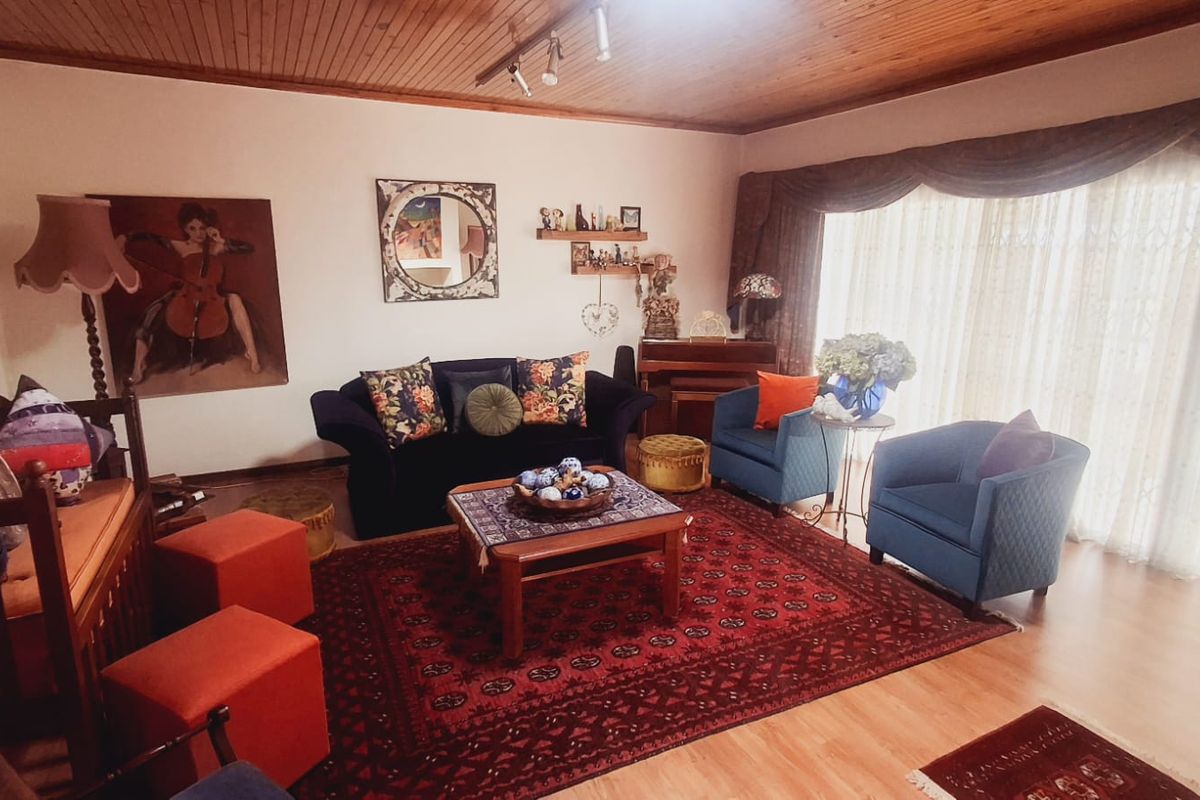 A cozy living room featuring warm timber ceilings, laminate flooring, and a large sliding glass door that provides ample natural light.