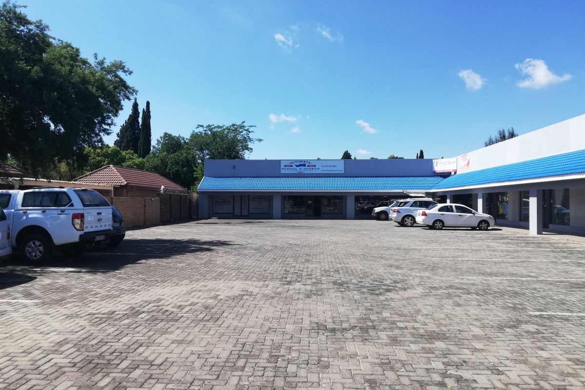 Commercial property exterior featuring a paved parking lot and storefront access with a blue tiled roof.