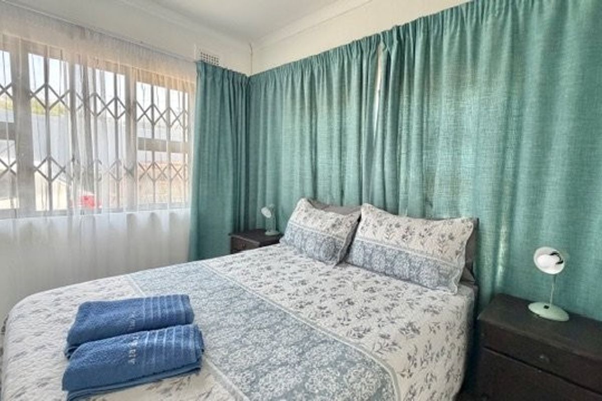 A functional bedroom featuring a window with an integrated security gate and decorative ceiling cornicing.