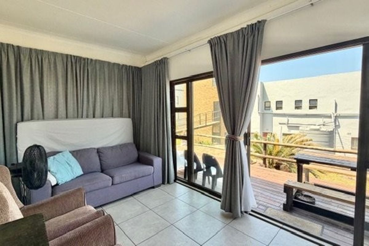 A living room featuring tiled flooring and large sliding glass doors that provide access to an outdoor deck area.