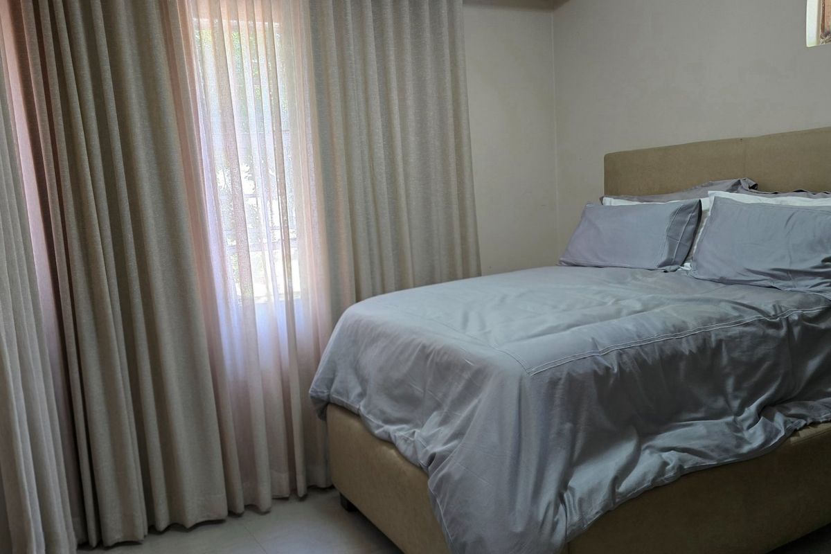 A functional bedroom featuring tiled flooring and floor-to-ceiling curtain treatments, providing a neutral base for interior design updates.