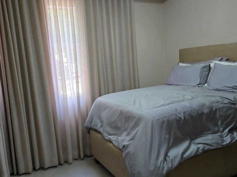 A functional bedroom featuring tiled flooring and floor-to-ceiling curtain treatments, providing a neutral base for interior design updates.