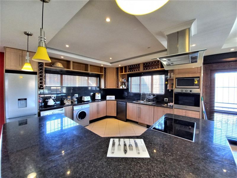 Spacious kitchen featuring granite countertops, built-in oven, extractor fan, and ample cabinetry with integrated appliances and modern recessed lighting.