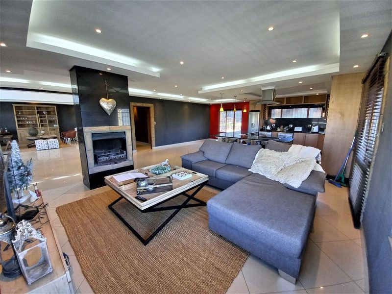 Spacious open-plan living area featuring a central fireplace, modern kitchen with island, and recessed ceiling lighting throughout.