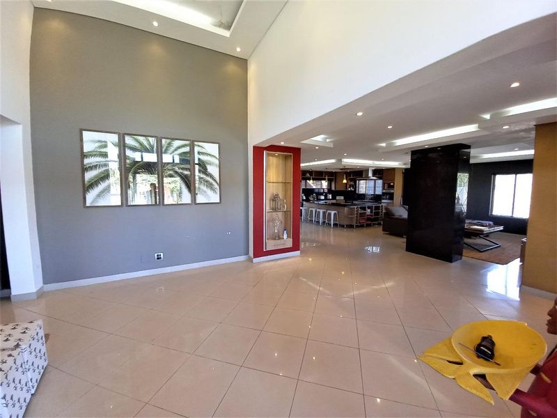 Spacious open-plan living area featuring high ceilings, recessed lighting, polished tile flooring, and a seamless transition into a modern kitchen space.