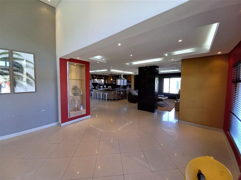 Spacious open-plan living and kitchen area featuring high ceilings, recessed lighting, tiled floors, and a modern kitchen island with integrated cabinetry.
