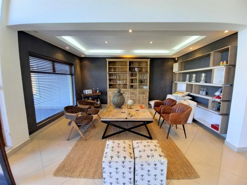 A well-lit living room featuring tiled flooring, recessed ceiling lighting, and custom built-in shelving units.