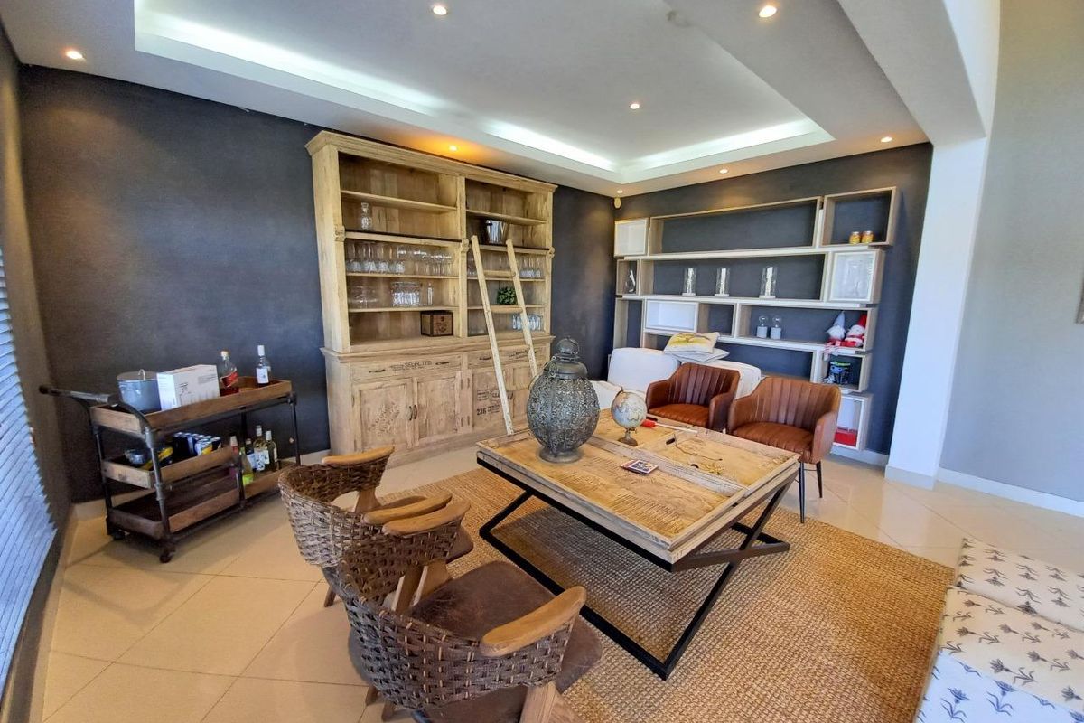 Spacious living room featuring a recessed ceiling with cove lighting, tiled flooring, and extensive built-in shelving units.