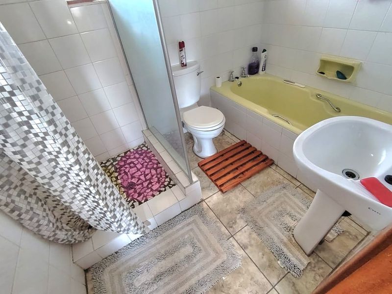 A functional bathroom featuring a pedestal basin, toilet, shower enclosure, and a built-in bathtub with tiled finishes throughout.