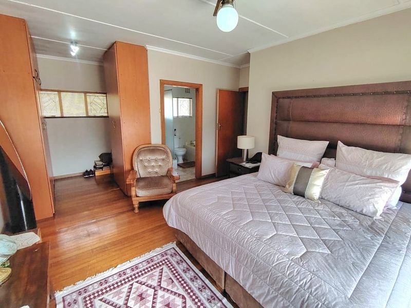 Spacious bedroom featuring hardwood flooring, built-in cupboards, and direct access to an en-suite bathroom.