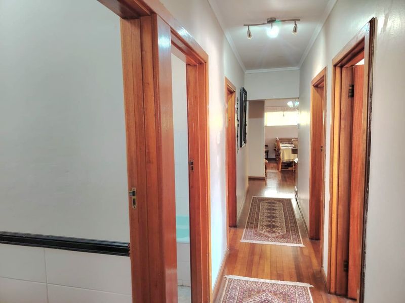 A well-maintained hallway featuring warm wooden flooring and classic timber door frames, providing access to multiple rooms within the home.