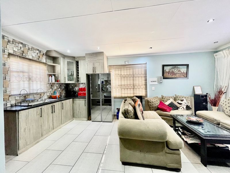 Spacious open-plan living area featuring a modern kitchen with built-in cabinetry, stone countertops, and tiled flooring throughout.