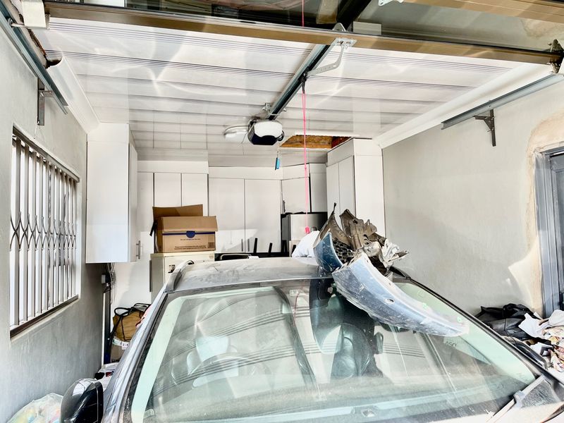 A functional garage space featuring built-in storage cabinetry, a motorized garage door system, and security bars on the window.