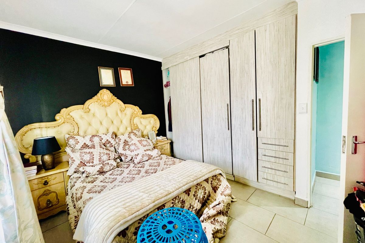 A bedroom featuring built-in cupboards with light wood-grain finish and tiled flooring.