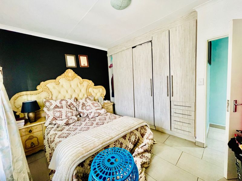 A bedroom featuring built-in cupboards with light wood-grain finish and tiled flooring.