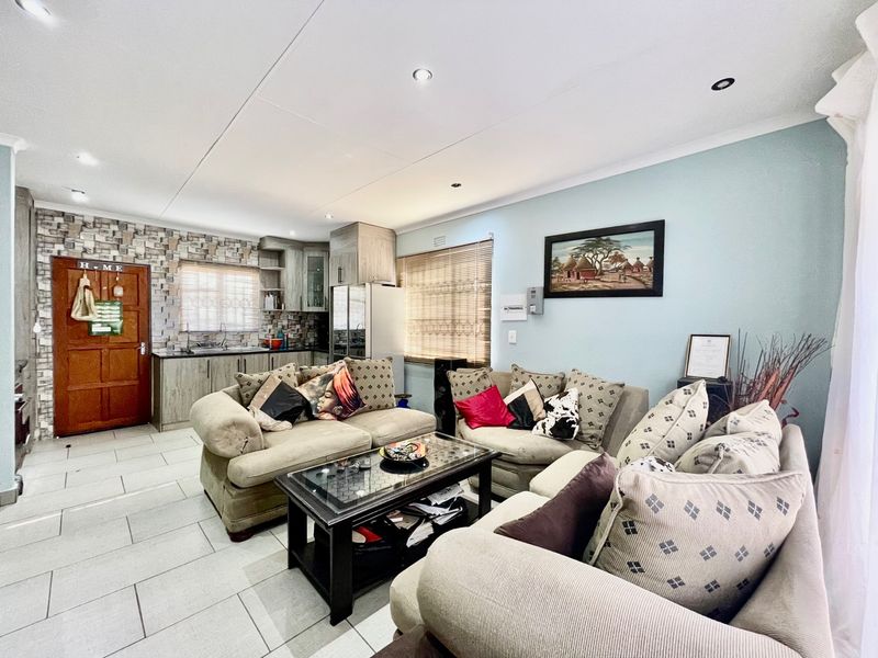 Open-plan living area featuring tiled flooring, recessed lighting, and a compact kitchen with built-in cabinetry and a decorative stone-look feature wall.