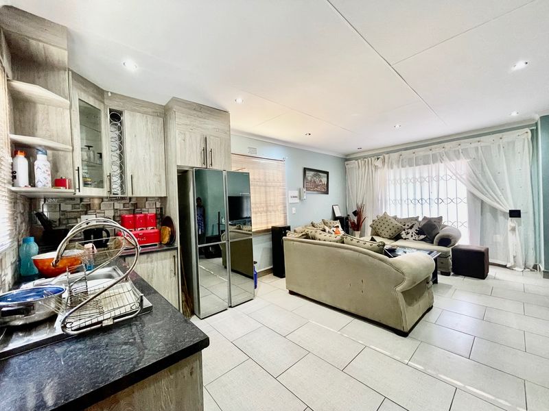 Open-plan living area featuring a modern kitchen with stone countertops, ample cabinetry, and tiled flooring, seamlessly flowing into the adjacent lounge space.