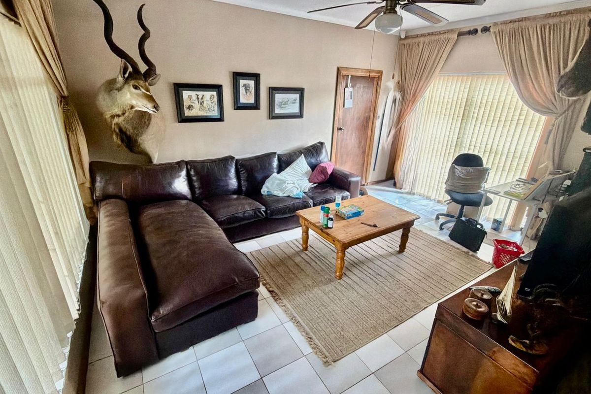 A living room featuring tiled flooring, a ceiling fan, and a sliding glass door providing access to the exterior.