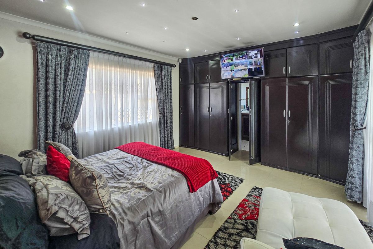 Spacious bedroom featuring extensive dark wood built-in cabinetry, tiled flooring, and recessed downlighting, offering ample storage and a clean, functional layout.