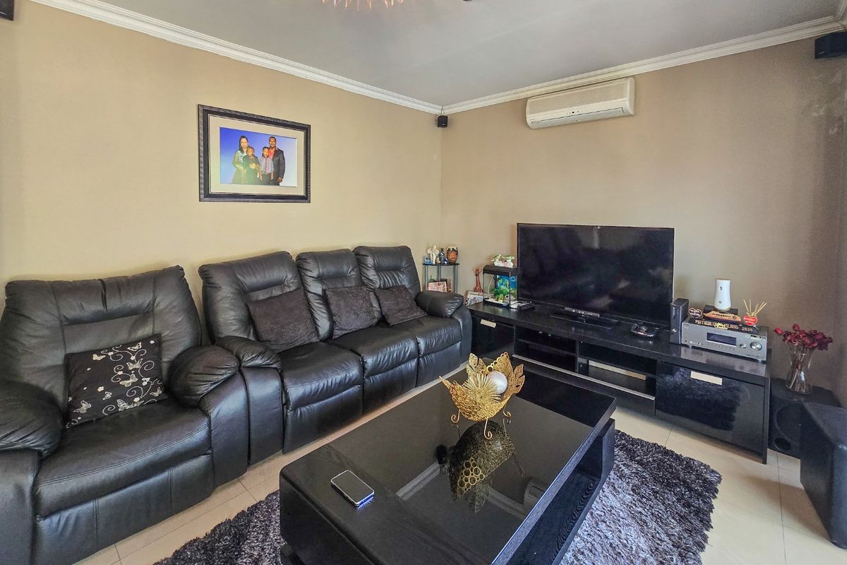 A comfortable living room featuring tiled flooring, a split-system air conditioner, and decorative ceiling detailing.