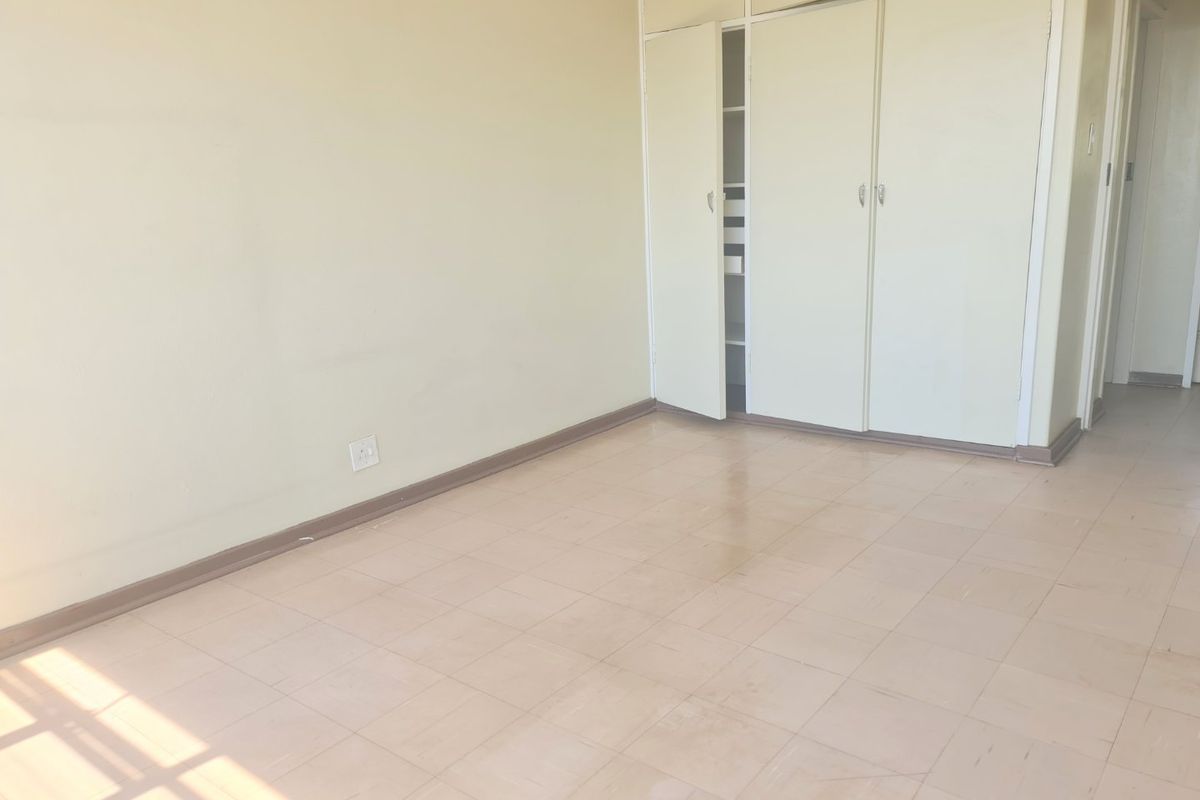 An empty bedroom featuring built-in cupboards and tiled flooring, offering a blank canvas for renovation or interior design updates.