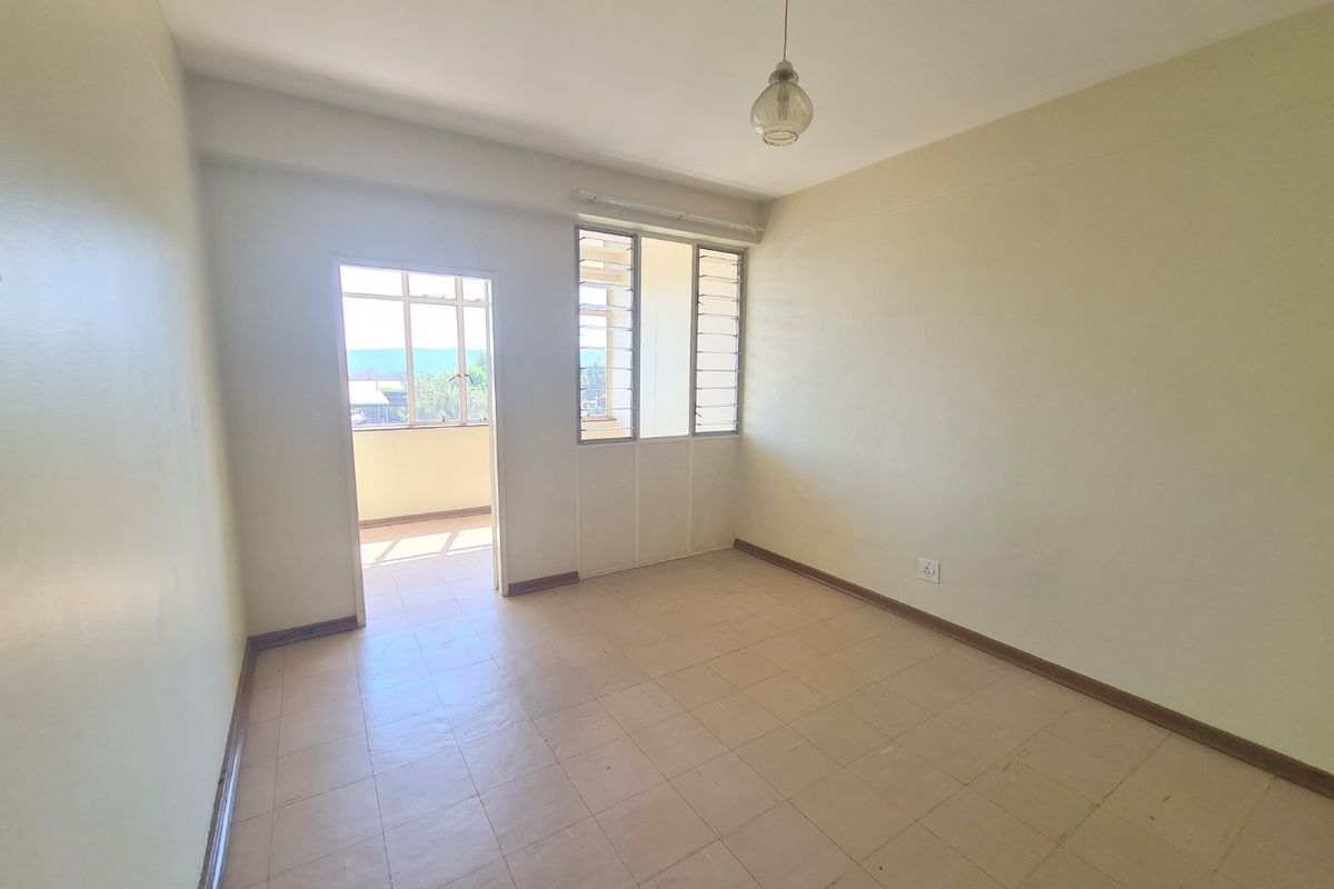 A vacant bedroom featuring tiled flooring, louvered windows, and access to an adjoining balcony area.