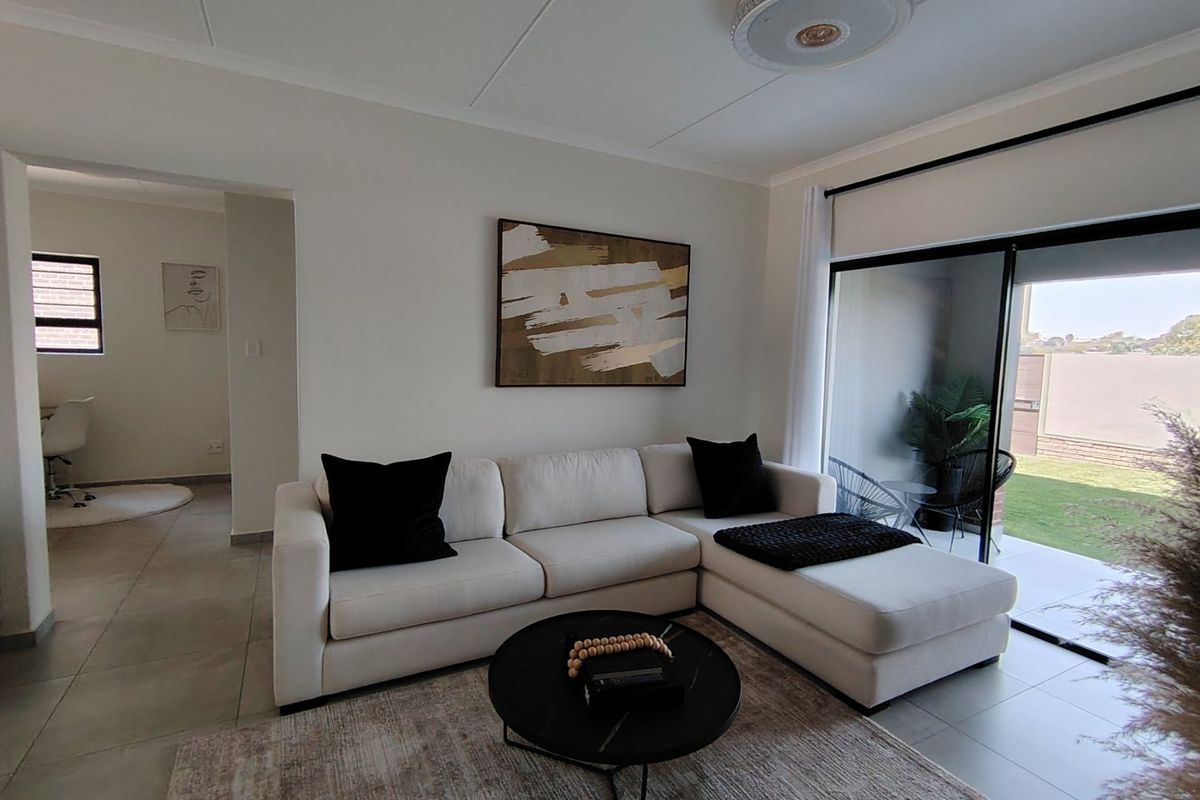 A bright and modern living room featuring tiled flooring and a large sliding glass door that provides seamless access to the outdoor patio area.