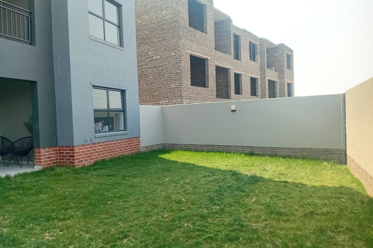 A private rear garden area featuring a lawn, boundary wall, and access to the apartment's exterior facade.