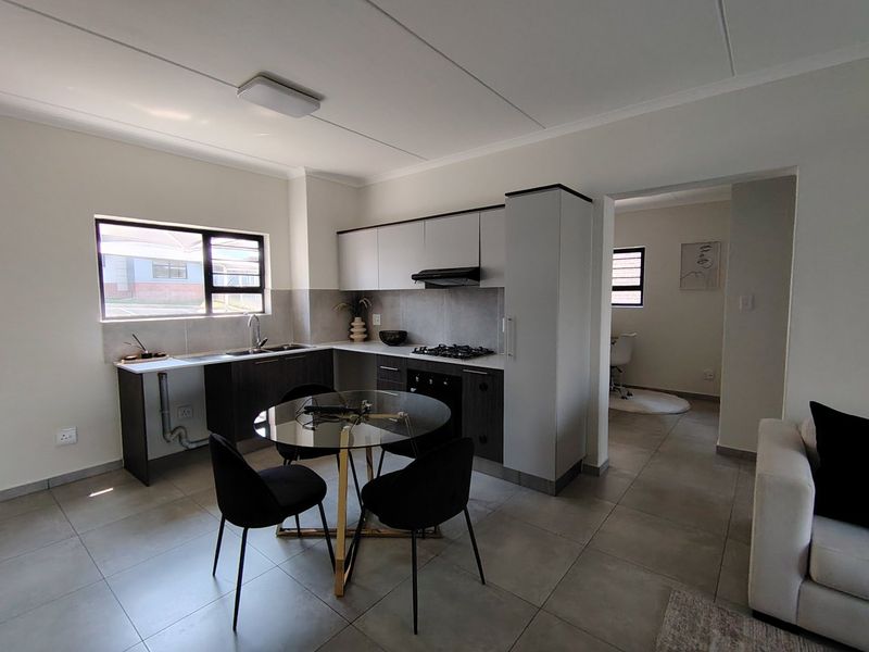 Modern open-plan kitchen and living area featuring contemporary cabinetry, gas hob, and tiled flooring, offering a functional and bright living space.