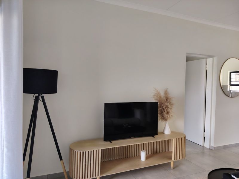 A bright and neutral living area featuring modern tiled flooring and clean wall finishes, providing a versatile space for relaxation.